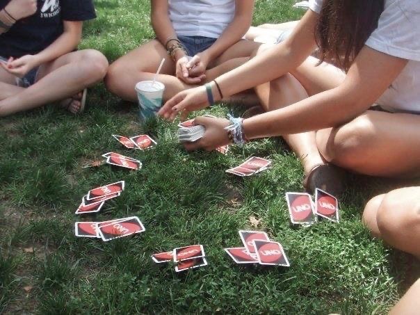 Older kids playing a quiet card game together in the grass