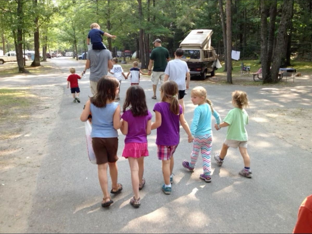 A parent and children walking together outdoors in warm sunlight